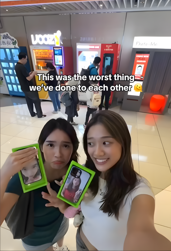 Two friends customizing funny phone cases for each other at a vending machine
